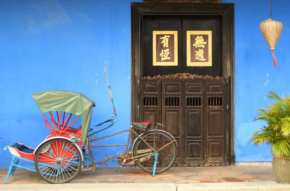 Tricycle parked in front of large brown door in Penang, Malaysia