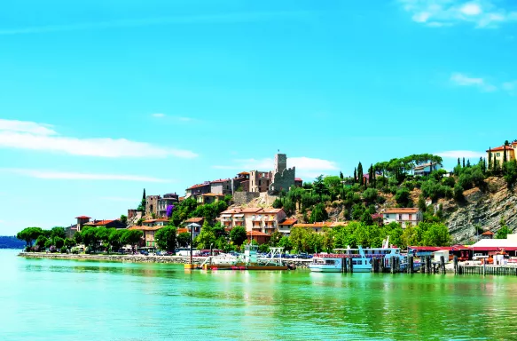 Brightly coloured Lake Trasimeno with anchored boats in the province of Perugia, Umbria, Italy.