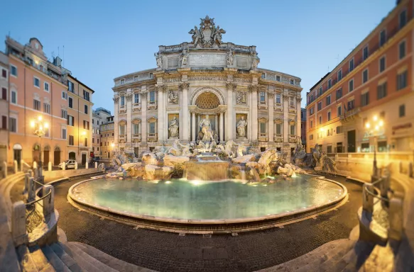 Late afternoon view of Trevi Fountain with illuminated streetlights in Rome, Italy