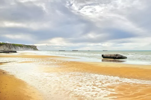 Yellow sand with glistening water on the Arromanches WWII Beach