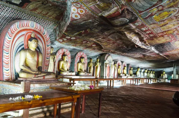 Interior of the Dambulla Golden Cave Temple with rows of golden Buddha statues and painted ceilings, Sri Lanka, South Asia.