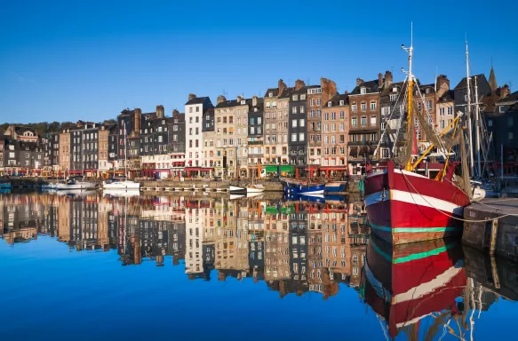 Boats and a row of narrow houses overlooking the Honfleur Harbour in France