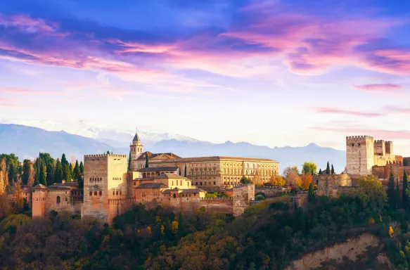 Alhambra palace  with Sierra Nevada mountains and a colourful sky in Granada, Spain