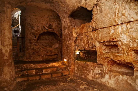 Underground in St Paul’s Catacombs, smooth carved stone walls featuring shelves to lay created for a Christian resting place, Malta