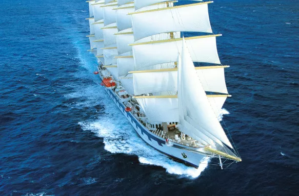 Royal Clipper in transit across the ocean with multiple white sails deployed  