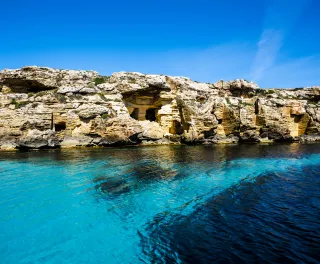 Shallow blue ocean with a background of coastal rocks 